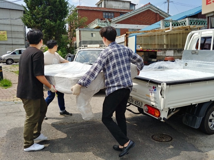 의정부시 신곡1동 행정복지센터 직원들이 아일랜드캐슬 호텔&리조트가 기부한 1인용 침대 매트리스를 선정된 가구에 전달하고 있다. (사진설명)