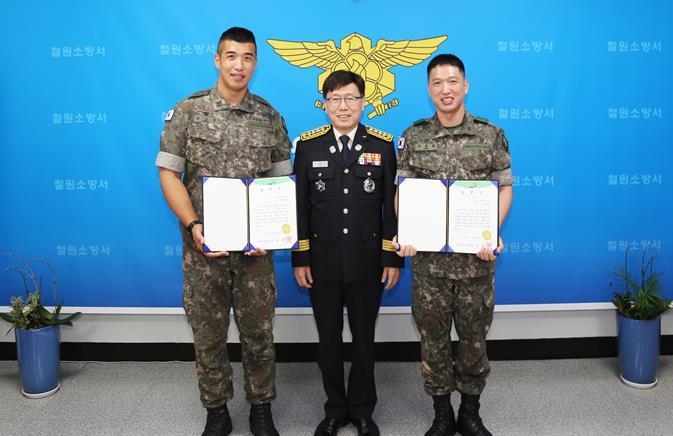 육군 1기갑여단 최고봉 중사(왼쪽)와 우용희 중사(오른쪽)가 남흥우 철원소방서장(가운데)로 부터 표창장과 하이 세이버 인증서 및 배지를 수여받았다.(사진설명)
