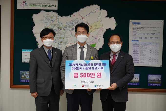 의정부시시설관리공단 임해명 이사장(오른쪽)과 홍정길 본부장(왼쪽)이 소외계층 돕기 성금 500만원을 기탁후 황범순 부시장(가운데)과 기념촬영하고 있다.(사진설명)